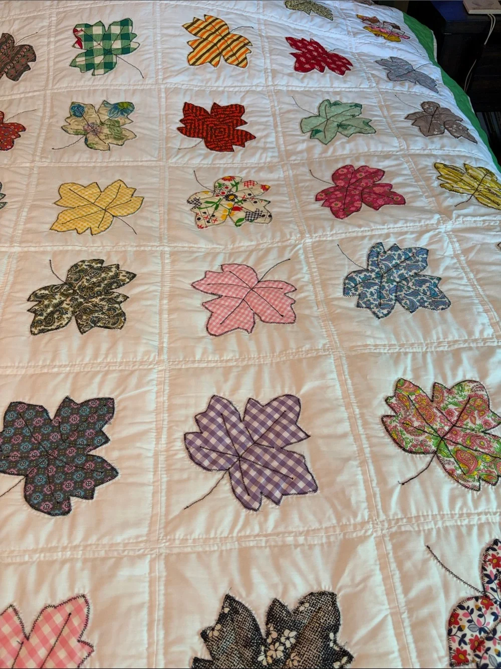 Vintage quilt handcrafted with color leaf blocks on white with green trim